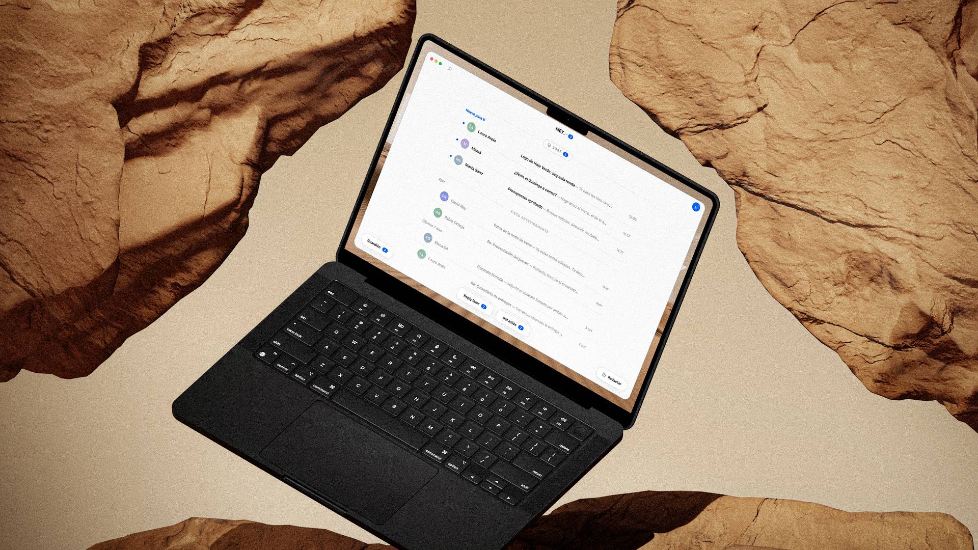 A black MacBook among sandstone rocks, with MEY's inbox on the screen
